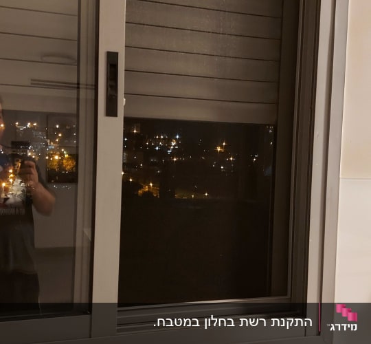 חלון אלומיניום עם תריסים סגורים בלילה